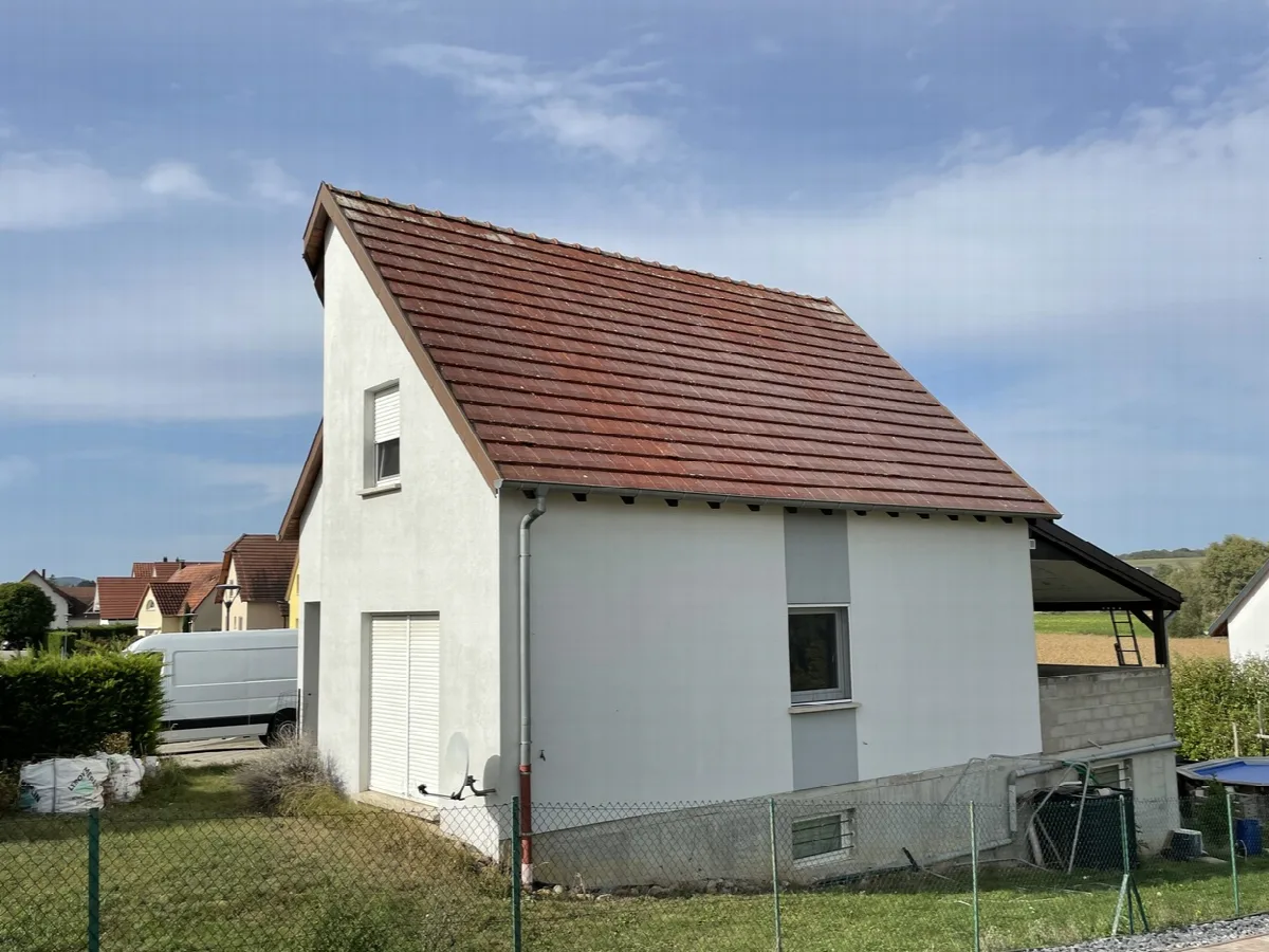 Pan de toiture en tuiles, rive et gouttière sur une maison blanche